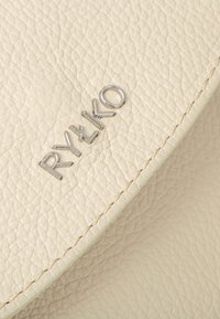 Borsa in pelle crema con superficie texturizzata, caratterizzata da un logo argento "RY&KO" e cuciture visibili lungo i bordi.