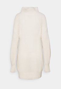 Pull en maille confortable de couleur crème avec un col montant, des manches longues et une coupe décontractée. Présente un motif texturé et des poignets côtelés.