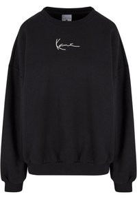 Svart hettegenser med rund hals, ribbestrikkede mansjetter, senkede skuldre og brodert hvitt logo på brystet. Mykt stoff med en avslappet passform.