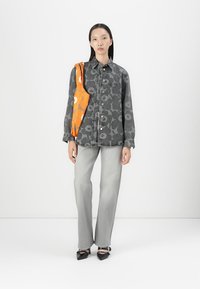 Gray patterned denim jacket with a relaxed fit. Paired with light gray straight-leg jeans and black shoes. An orange scarf is draped over the shoulder.