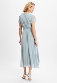 Lichtblauw, jurk tot de knie met korte vlindermouwen, een getailleerde taille en een vloeiende rok. Voorzien van een rits aan de achterkant.