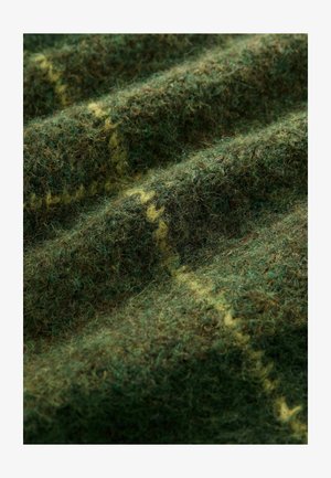 Villane kangas, millel on tekstuurne pind tumerohelistes ja pruunides toonides, kus juures kiudude vahel jookseb silmapaistev kollakas muster.