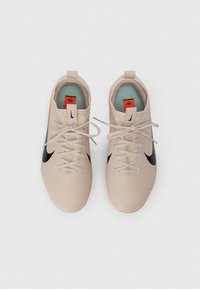 Αθλητικά παπούτσια σε απαλό ροζ χρώμα με μαύρες λεπτομέρειες, υφή στην εξωτερική επιφάνεια, κο�ύμπωμα με κορδόνια και πορτοκαλί λογότυπο στη γλώσσα και τη σόλα.