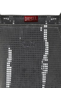 Borsa grigia con un'esterno testurizzato a motivo quadrato. Presenta un'etichetta rossa con il logo "DIESEL" e un logo ovale in rilievo sulla superficie.