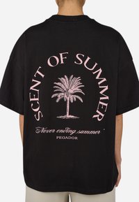 Camiseta de algodón negra con un gran gráfico en rosa de una palmera que lleva el texto "AROMA DE VERANO" y "Verano sin fin" abajo.