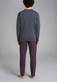 Completo da loungewear da uomo con una maglietta a maniche lunghe grigia e pantaloni del pigiama a scacchi in rosso scuro e blu navy dal tocco morbido.