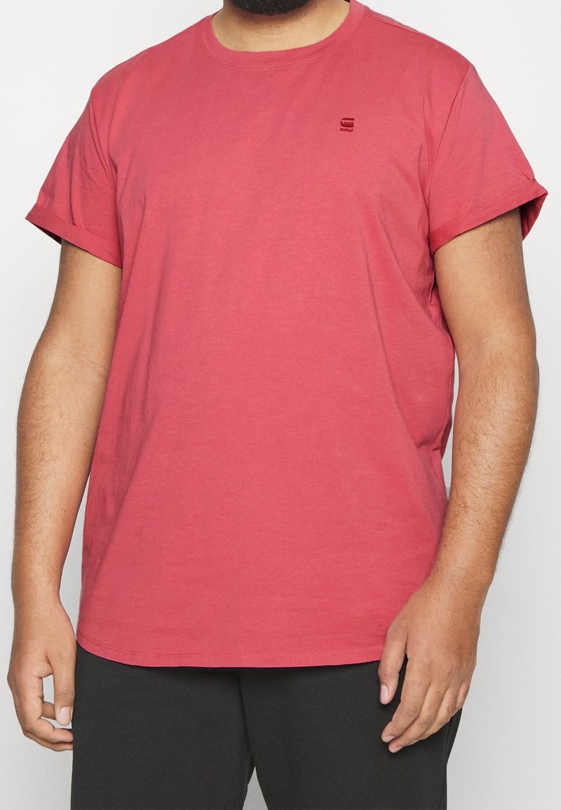 T-shirt en coton rouge avec des manches courtes, un col rond et un petit logo imprimé sur la poitrine. Présente une coupe décontractée.