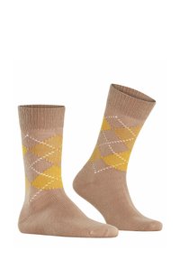 Beige Baumwollsocken mit einem argyle Muster aus gelben und weißen Rauten. Gerippter Bund, glatte Textur und mittellange Länge.