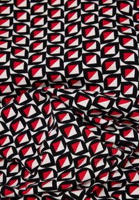 Musterstoff mit einem geometrischen Design aus roten, schwarzen und weißen Quadraten und Rauten, das eine strukturierte Optik erzeugt.
