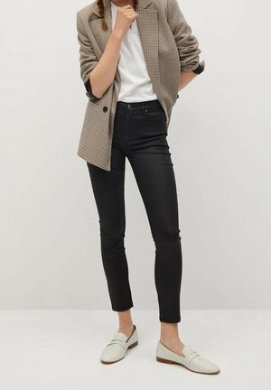 Černé slim-fit džíny kombinované s houndstooth sakem, bílým tričkem a smetanovými polobotkami, s přizpůsobeným designem a hladkým povrchem.