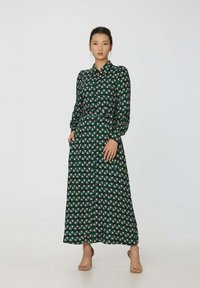 Robe à manches longues verte avec un motif géométrique de petits carrés rose et blanc, ceinturée à la taille, avec un col.