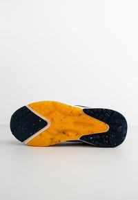 Yellow and black outsole with textured grip pattern, featuring colorful specks. Rounded toe, smooth edges, durable rubber material.