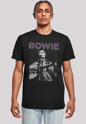 Black t-shirt featuring a graphic of a man playing guitar in a patterned shirt. The word "BOWIE" is printed in bold, purple text above the image.