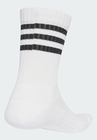 Calzino bianco in cotone con texture a coste, caratterizzato da tre righe orizzontali nere nella parte superiore. Le aree del tallone e delle dita sono rinforzate.