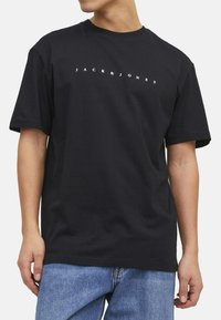 Sort bomuld T-shirt med korte ærmer, der har et hvidt trykt logo "JACK & JONES" på brystet. Klassisk crew neck design.