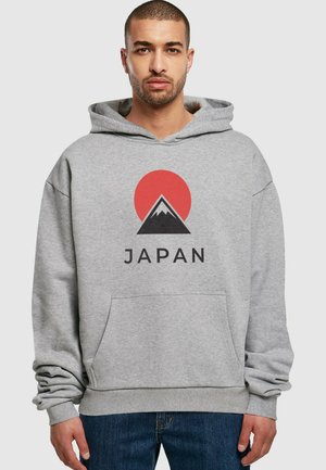 Grå hettegenser med frontlomme, med et rødt sol- og fjellmotiv, og ordet "JAPAN" skrevet med svart under designet.
