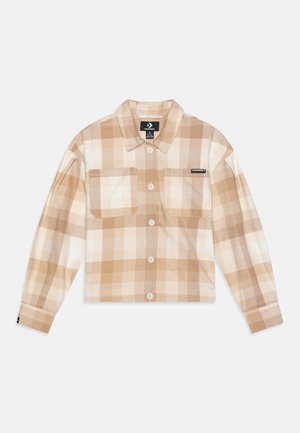 Chemise écourtée à carreaux beige et crème, avec un devant boutonné, deux poches poitrine et un col. Fabriquée dans un tissu doux.