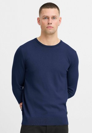 Granatowy sweter dzianinowy z okrągłym dekoltem i długimi rękawami; lekki materiał i żebrowany dół; dobrze przylega w mankietach.