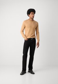 Light beige long-sleeve sweater, slim fit, with a round neckline; paired with black straight-leg pants and black lace-up shoes.