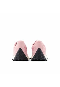 Zapatillas deportivas rosas con parte superior de tejido texturizado y suela de goma negra en forma de triángulo. Presentan un talón redondeado y detalles sutiles.