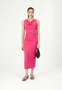 Fukszia ruha galléros nyakkivágással, testhez simuló sziluettel, középhosszú, sima textúrával, fekete pántos szandálokkal és egy táskával párosítva.