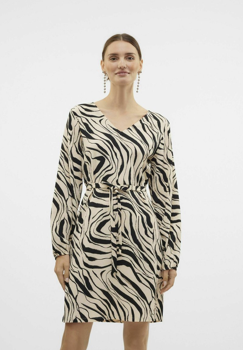 Zebraprint jurk in crèmekleur en zwart, met v-hals ontwerp, lange mouwen, ceintuur in de taille, gestructureerde stof, knielengte met vloeiende silhouette.