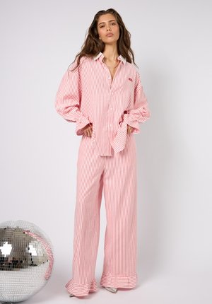 Komplet piżamowy w czerwono-białe paski, składający się z koszuli na guziki z kołnierzykiem oraz spodni z szerokimi nogawkami zakończonymi falbankami; miękki materiał.