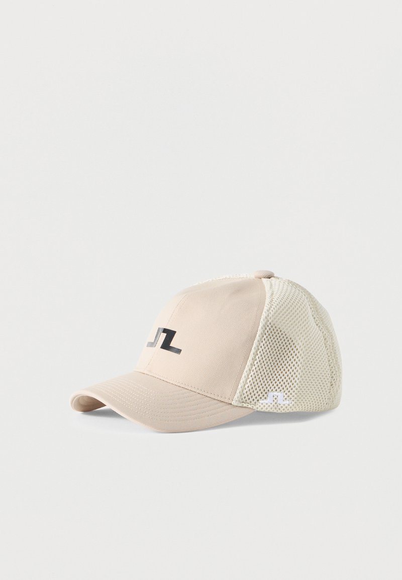 Μπεζ καπέλο μπέιζμπολ με πίσω πάνελ από δίχτυ και μαύρο-άσπλο λογότυπο μπροστά και στο πλάι, τοποθετημένο σε λευκό φόντο.