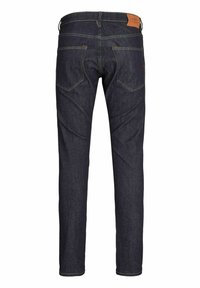 Jeans de mezclilla azul oscuro con corte ajustado, con costuras amarillas en contraste, dos bolsillos traseros y una etiqueta de cuero marrón en la cintura.