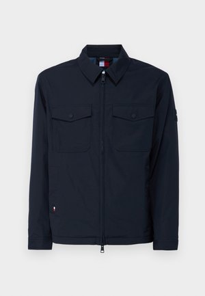 Casaco azul-marinho feito de material leve, com fecho de zíper, dois bolsos no peito e um discreto logótipo na manga.