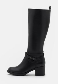 Botas negras hasta la rodilla hechas de cuero suave con un tacón grueso, que cuentan con una correa decorativa de cadena alrededor del tobillo.