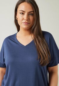 Marinblå V-ringad t-shirt i mjukt tyg med korta ärmar. Har en avslappnad passform och en slät textur, vilket gör den lämplig för avslappnad användning.