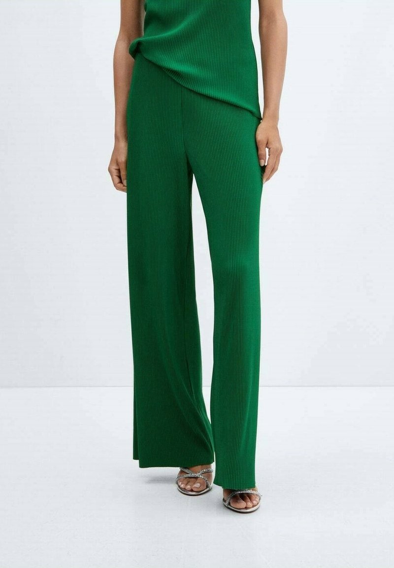 Pantalons larges côtelés verts avec une taille haute, assortis d'un haut du même couleur. Le tissu présente des rayures verticales pour ajouter de la texture.