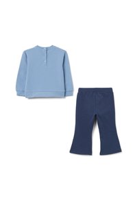 Sweatshirt bleu clair à manches longues avec trois boutons dans le dos, associé à un pantalon évasé bleu marine, sur fond blanc.