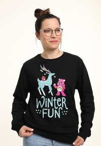Zwarte sweatshirt met kleurrijke cartoonafbeeldingen van een rendier en een beer, met de tekst "WINTER FUN" in speelse letters.