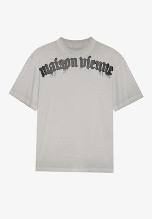 Grå bomulls t-skjorte med løs passform, med svart dryppende tekst "maison vieme" over forsiden. Korte ermer og rund hals.
