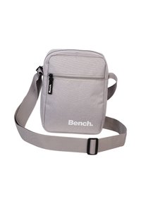 Grau gewebte Schultertasche mit verstellbarem Riemen, frontaler Reißverschlusstasche und weißem "Bench."-Logo. Glatte Textur, rechteckige Form, minimalistisches Design.