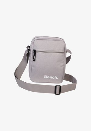 Grau gewebte Schultertasche mit verstellbarem Riemen, frontaler Reißverschlusstasche und weißem "Bench."-Logo. Glatte Textur, rechteckige Form, minimalistisches Design.