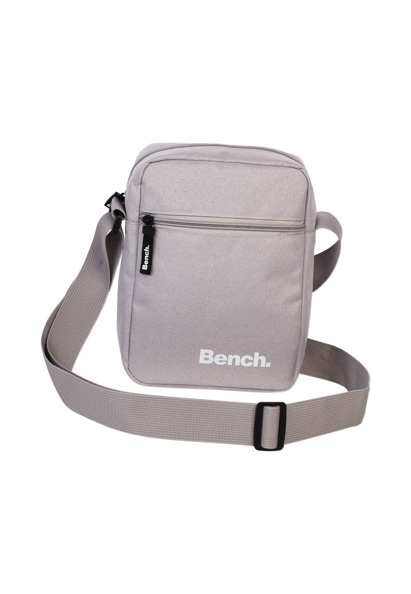 Grau gewebte Schultertasche mit verstellbarem Riemen, frontaler Reißverschlusstasche und weißem "Bench."-Logo. Glatte Textur, rechteckige Form, minimalistisches Design.