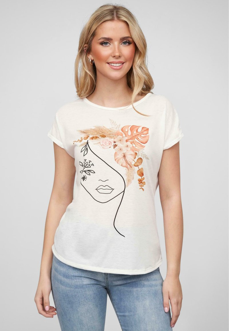 T-shirt crème en tissu doux avec un design de visage tracé à la main orné d'accents floraux dans des tons pêche et vert. Manches courtes.