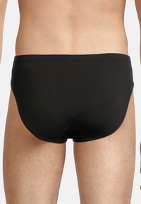 Slip neri aderenti con una texture liscia, vita elastica e senza pattern o decorazioni visibili, progettati per il comfort.