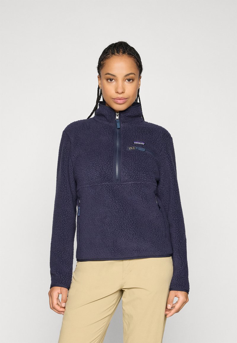 Navy blue fleece pullover with a zippered neck, textured exterior, chest pocket, and side pockets, featuring a brand logo on the left chest.
