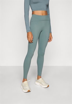 Tealfargede tights med høyt liv, laget av et glatt og elastisk materiale. Kombinert med lyse joggesko med nettingdesign og gummisåle.