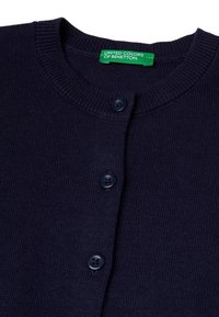 Námořnický pletený kardigan s kulatým výstřihem, dvěma knoflíky a zelenou etiketu s nápisem "UNITED COLORS OF BENETTON" na límci.