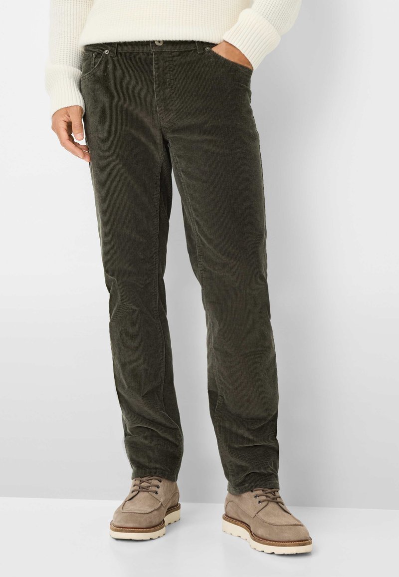 Donkergroene corduroy broek met verticale ribbels, voorzakken en een slim fit, gecombineerd met beige suède veterschoenen.