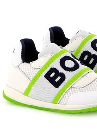 Witte sportschoenen met een mesh-design, voorzien van een groene accentband en "BOB" in marineblauw. Rubberen zool en gevoerde kraag voor comfort.