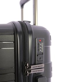 Maleta dura negra con superficie texturizada, cremalleras dobles, candado de combinación y un asa extensible para un transporte fácil.