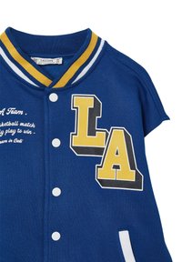 Niebieska koszulka z żółto-białym paskowanym kołnierzem, z napisem "LA" w pogrubionych grafikach, zapinana na guziki, z tekstem na przodzie.