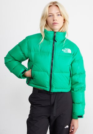 Chaqueta acolchada verde recortada con cuello alto y cierre de cremallera. Presenta un logo en el lado izquierdo del pecho y puños elásticos. Acabado mate, ligera.
