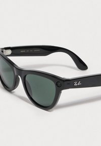 Gafas de sol Ray-Ban negras con lentes verdes, de forma clásica, acabado brillante y logotipo en la patilla. Incluye un pequeño detalle de cámara.